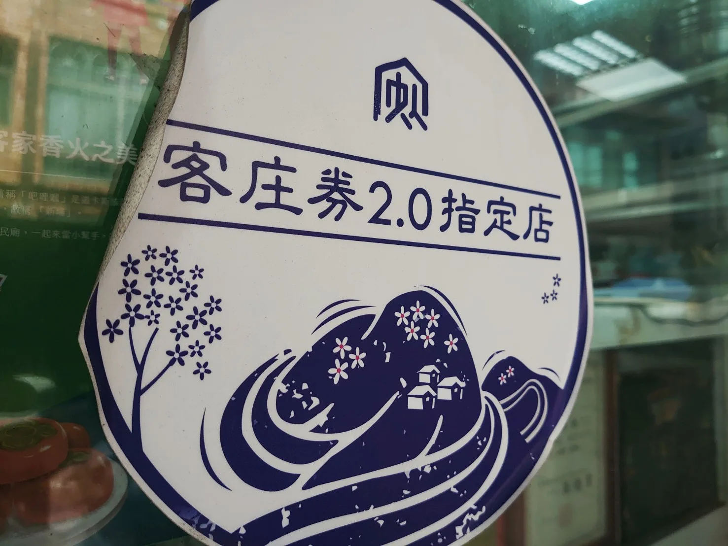 日勝飲食店的「客庄券2.0指定店」貼紙因為電動玻璃門而蜷曲,但完全不影響識別與客庄券抵用。李台源攝
