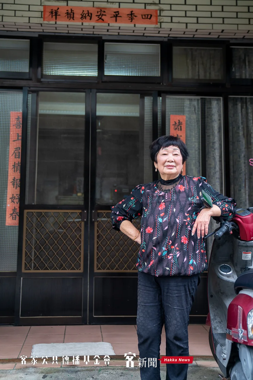 謝和枝站在自家門口倚著機車，她說她當年就是騎車機車去工廠上班。范修語攝