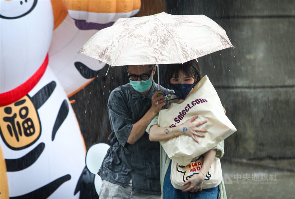 受對流雲系發展旺盛影響,中央氣象局24日下午針對14縣市發布大雨特報,其中台北市及新北市也同時發布大雷雨即時訊息。圖為台北市信義區民眾在大雨中共撐一把傘。圖/中央社