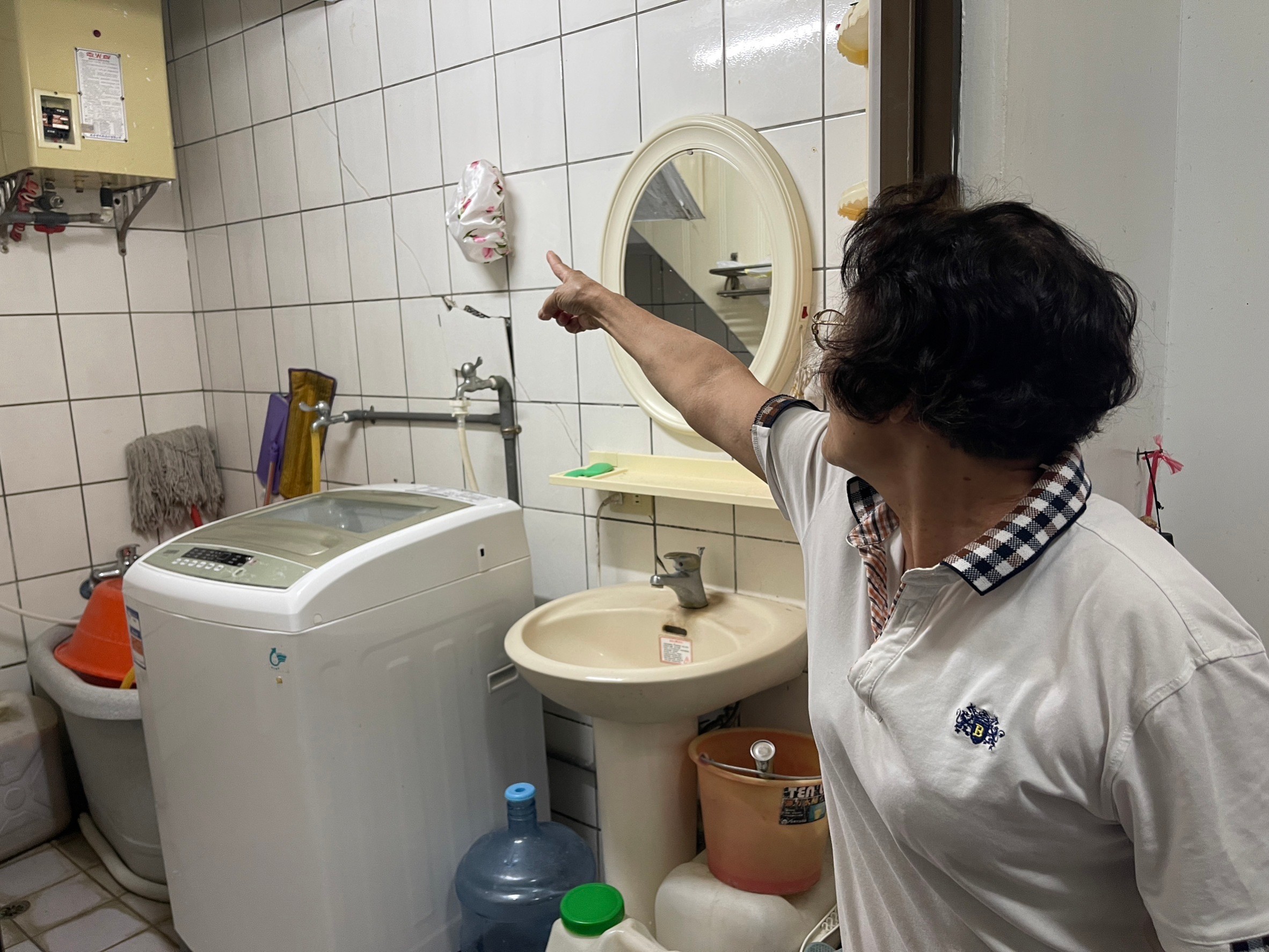 民眾指著浴室牆上的裂縫,磁磚裂痕相當明顯。宋佩遙攝