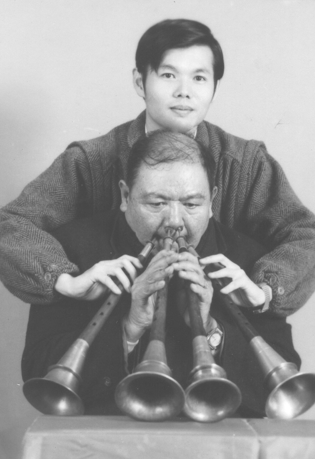 陳慶松是陳家八音團第三代傳人，他能同時吹奏四支嗩吶，他的孫子鄭榮興在背後幫忙按住嗩吶孔位。鄭榮興提供