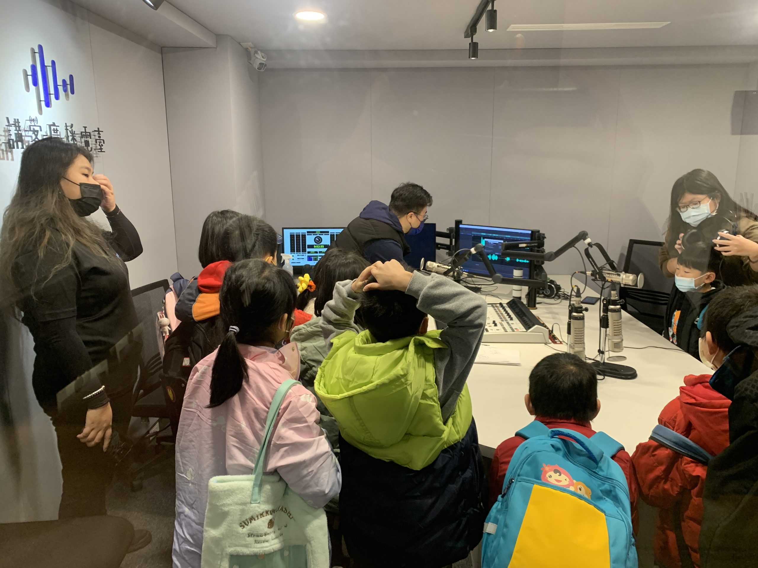 講客電臺同仁，正在幫學生戴上耳機，準備體驗廣播錄音。講客電臺提供