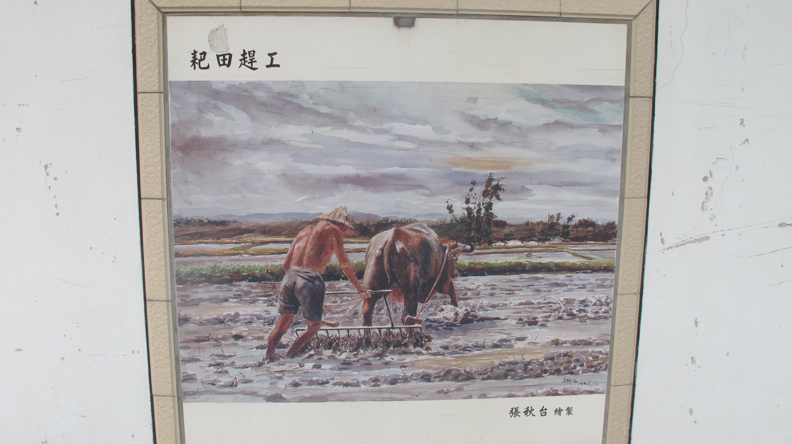 水彩畫家張秋臺畫筆下的「耙田趕工」，鑲嵌於糧食局苗栗糧管處外牆。何來美攝
