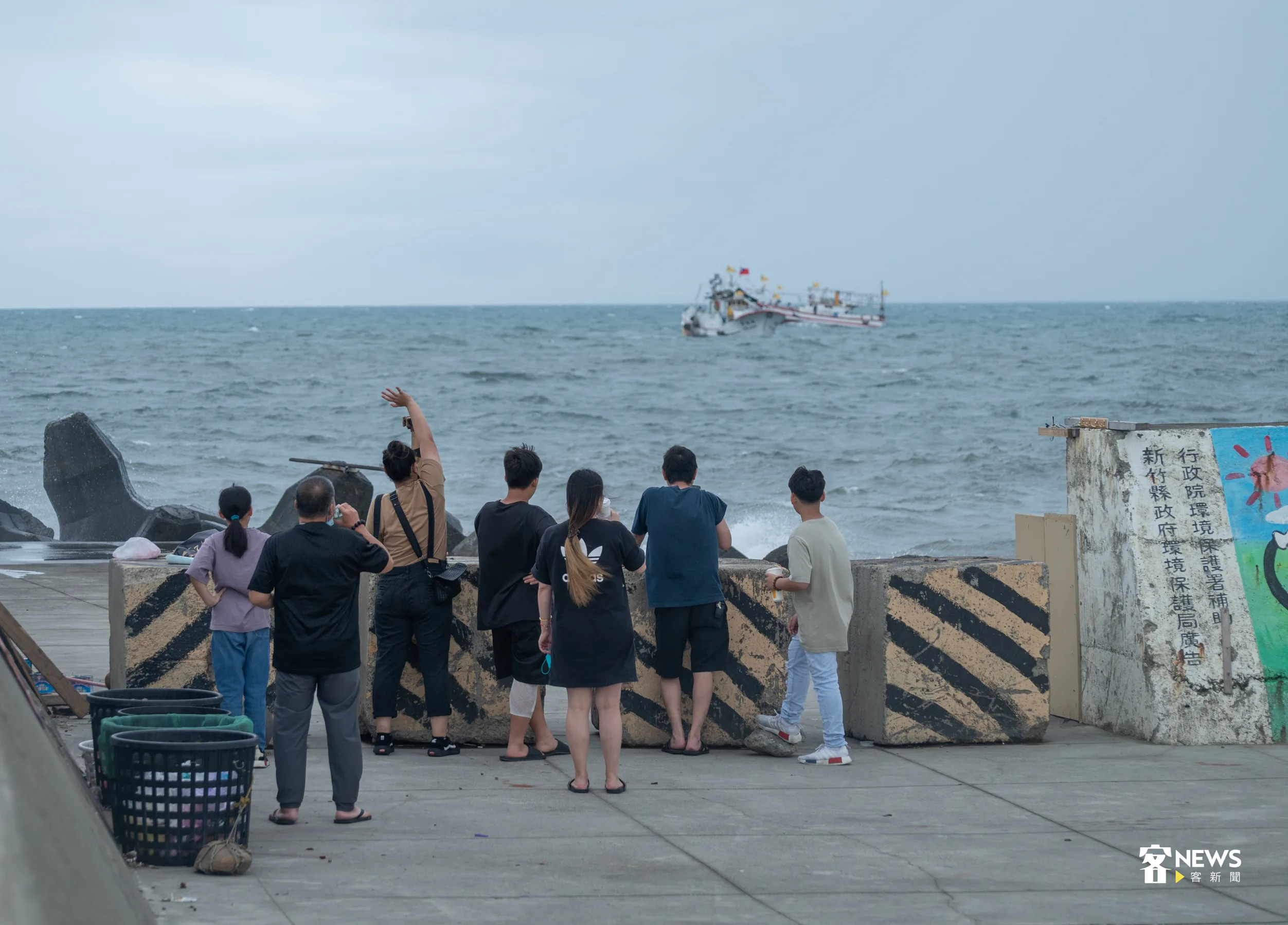 岸上民眾向海上遶境漁船揮手打招呼。洪俊傑攝