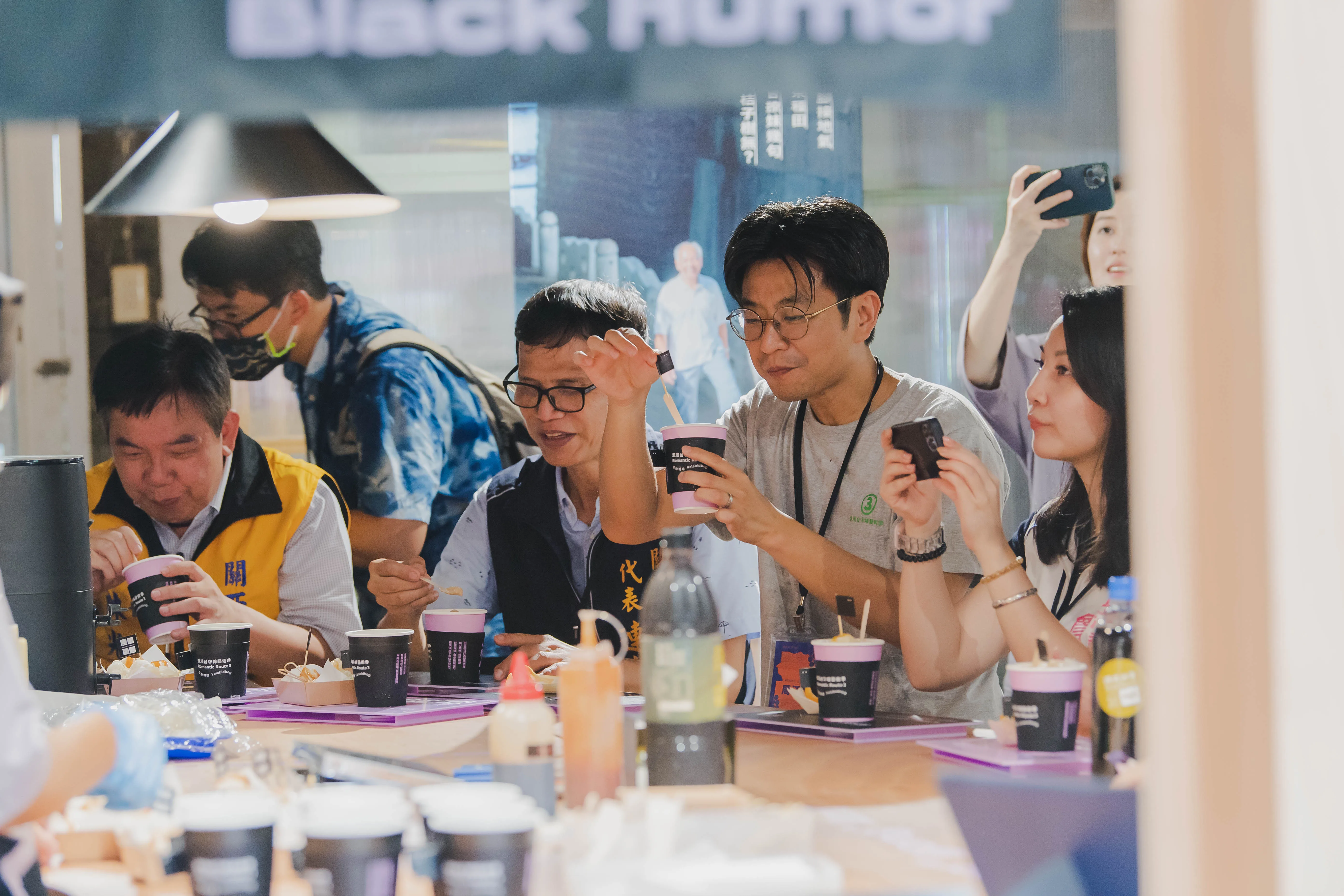 客委會副主委周江杰帶領在地代表一同於黑色幽默作品內享受客家美食。浪漫台三線藝術季提供