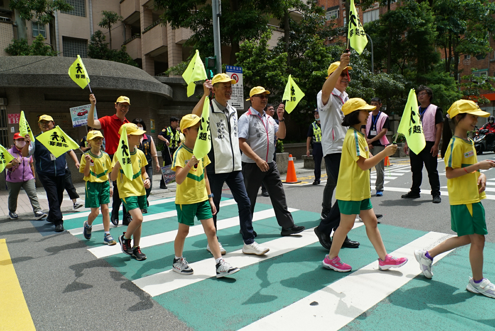 張善正與學童手舉小黃旗安全穿越斑馬線。桃園市政府提供
