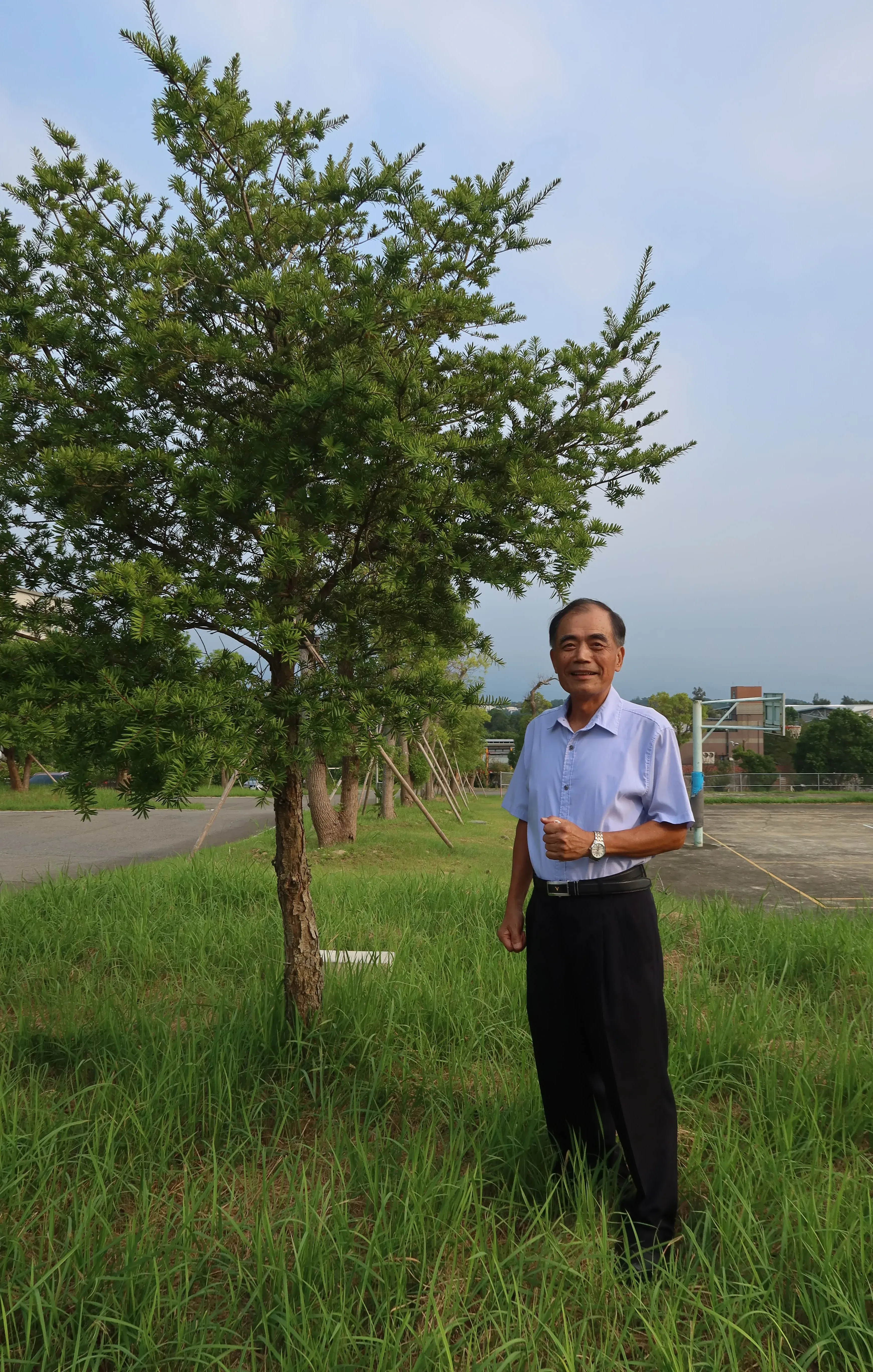 聯合大學副校長退休的李增欽,緬懷已故老同事黃富財,在紀念他的「先見之樹」前留影。何來美攝