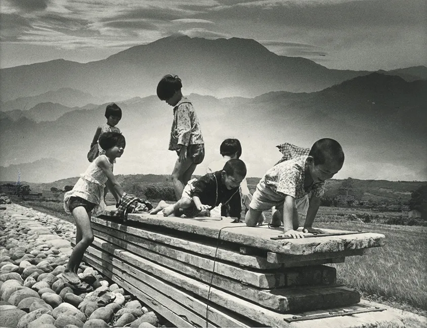 邱德雲，〈加里山下兒童樂〉，1970，國家攝影文化中心典藏。加里山下後龍溪堤防上，一群小朋友們在用來鋪設水底橋的木板上玩耍。國家攝影中心提供