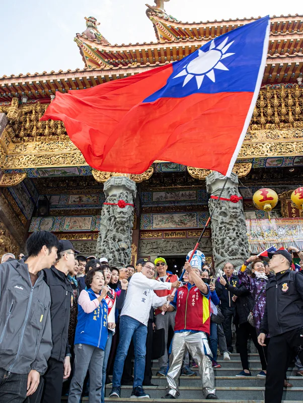 國民黨總統候選人侯友宜(前左,白衣)8日上午到台南市掃街拜票,在中樓勝安宮與支持者一同揮舞國旗,為選情造勢。<br />中央社