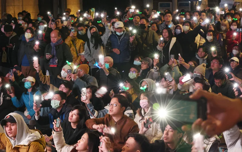 由民眾黨總統候選人柯文哲支持者主辦的「扛阿北守台灣」感恩晚會11日晚間在台北市北門廣場舉辦,儘管天氣冷颼颼,現場仍湧入不少人潮,許多人戴著小草造型頭飾高喊加油,在合唱主題曲時,民眾也點亮手機燈光隨音樂搖擺。中央社