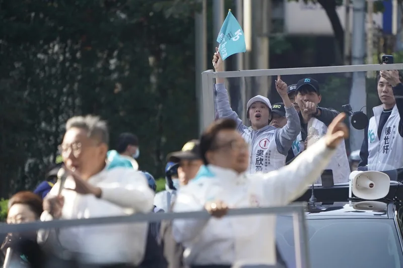 民眾黨副總統候選人吳欣盈(舉旗者)11日與民眾黨總統候選人柯文哲(前左)在台北市車隊掃街,吳欣盈高舉旗幟比出1號手勢催票。中央社