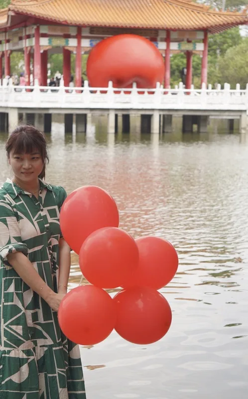 紅球台南歷史街區策展行動31日移展台南公園念慈亭,有民眾在南側臨湖處拿起紅色氣球取景,拍照留念。中央社
