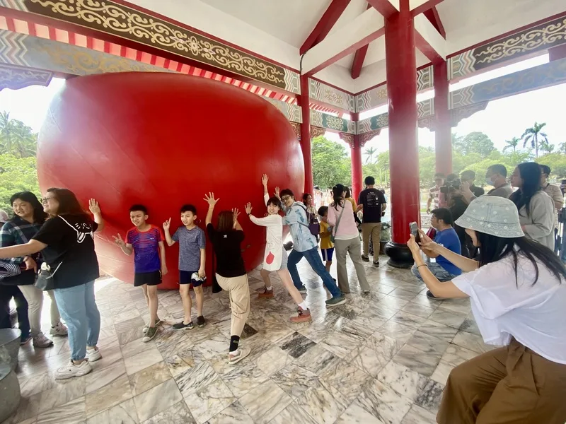 紅球台南歷史街區策展行動31日移展台南公園念慈亭,吸引許多民眾到場參觀,雙手扶著巨大紅球拍照留念。中央社
