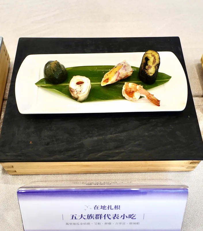 國宴第2道菜名為「在地扎根」，呈現5大族群代表小吃。其中酸辣蝦的白蝦來自嘉義布袋的品牌《邱家兄弟》。中央社