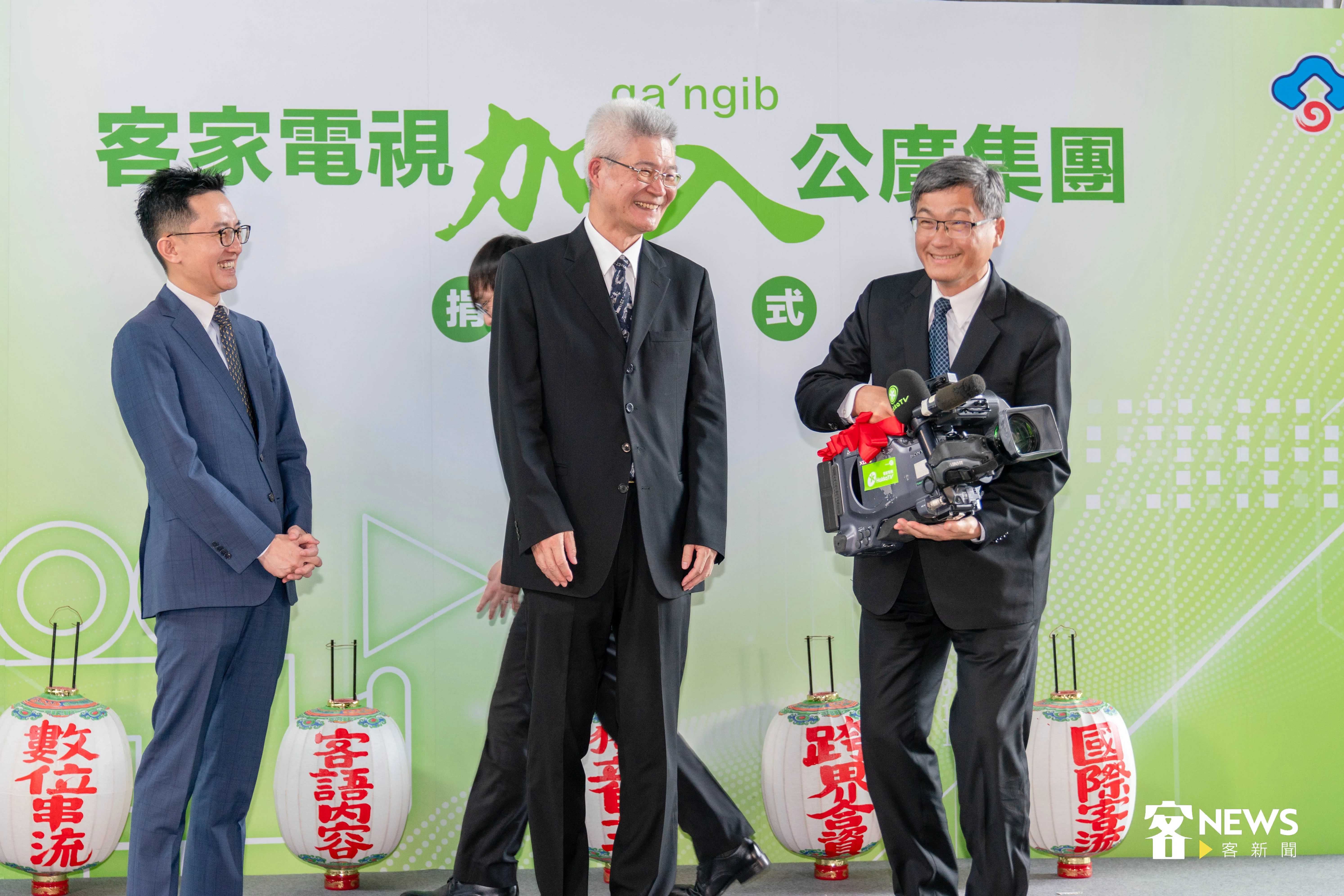 客委會主委楊長鎮（右）將象徵電視台的攝影機交接給公廣集團董事長胡元輝（中）和客家電視台長向盛言（左），楊長鎮舉起攝影機，笑稱份量非常重。范修語攝