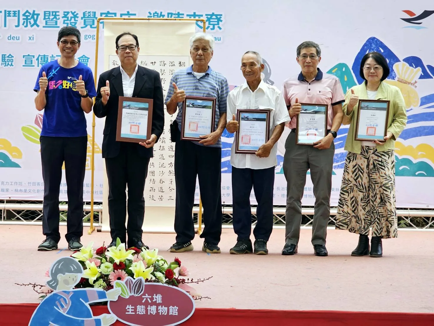 客發中心頒發感謝狀予六堆生態博物館共作共伴同盟的夥伴，感謝他們協助六堆的各項事務(左起客發中心何金樑主任、台糖公司屏東區處吳耀煌處長、佳冬蕭家管理人蕭義雄、新埤建功鍾屋管理人鍾展雄、客籍書法家宋雯賢、六堆運動會執行長曾耀群夫人李瑜珍)。客發中心提供