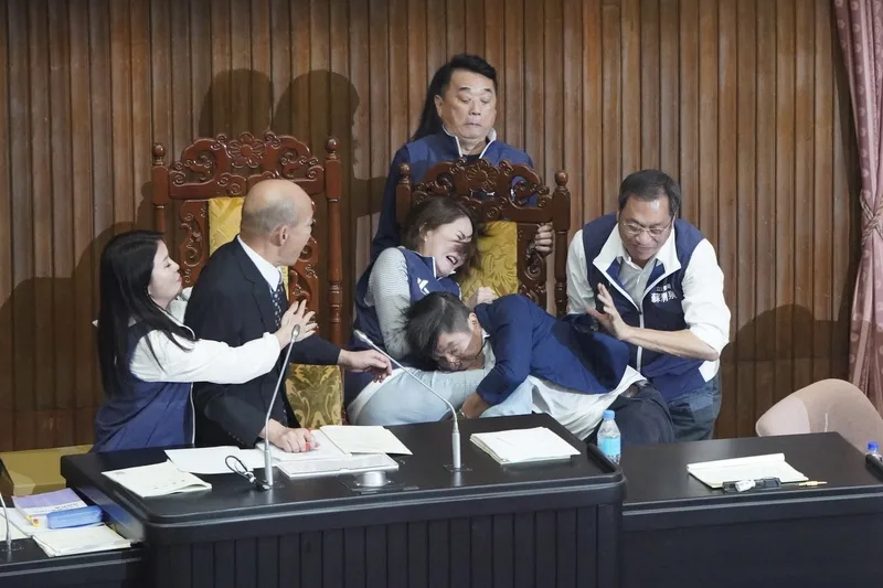 立法院會17日處理藍白所提國會改革法案，國民黨團、民眾黨團一早就占據議場主席台，民進黨立委則利用台上國民黨立委輪流回座位領取表決卡及表決的空檔，衝上主席台，藍綠爆發第2波推擠衝突。圖為民進黨立委鍾佳濱（前右2）一把抱住國民黨立委陳菁徽（前右3），兩人摔倒，國民黨立委蘇清泉（右）上前解圍。中央社