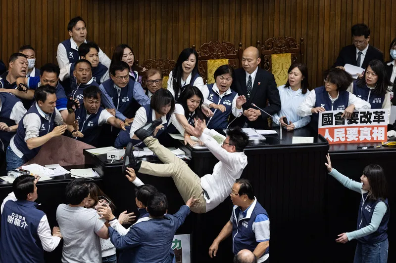 民進黨立委郭國文(卡其色長褲者)嘗試占領主席台以阻止會議繼續進行,朝野立委爆發衝突,過程中郭國文意外摔下主席台。中央社