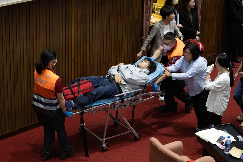 民進黨立委沈伯洋(中摔落者)被國民黨立委推落主席台,沈伯洋倒栽蔥摔下,頭部墜地受傷送醫。中央社