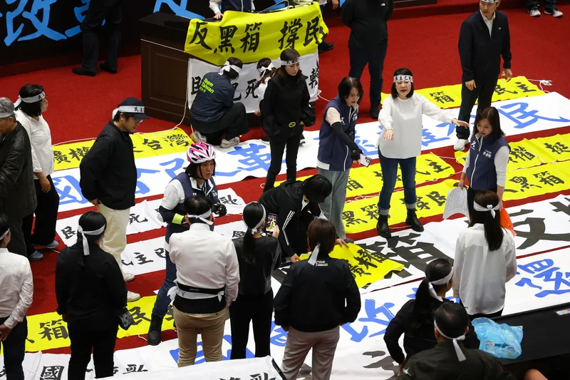 立法院會24日將繼續處理國會職權修正相關法案,一早藍、白合作順利占據主席台,圖為民進黨立委在議場內布置寫有「反黑箱 撐民主」、「反擴權 挺台灣」的布條表達訴求。中央社