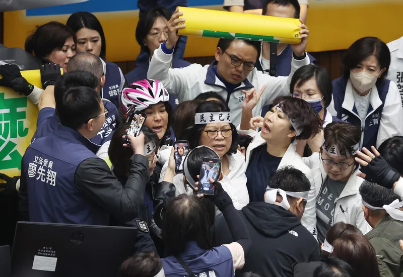 立法院會24日將續審國會職權修正相關法案,民進黨立委王美惠(中)、陳亭妃(中右)衝進主席台右側欲掛布條,但遭國民黨立委陳玉珍(中左)等人阻止,雙方爆發推擠,藍綠立委也相互不斷叫陣,場面一度火爆。中央社