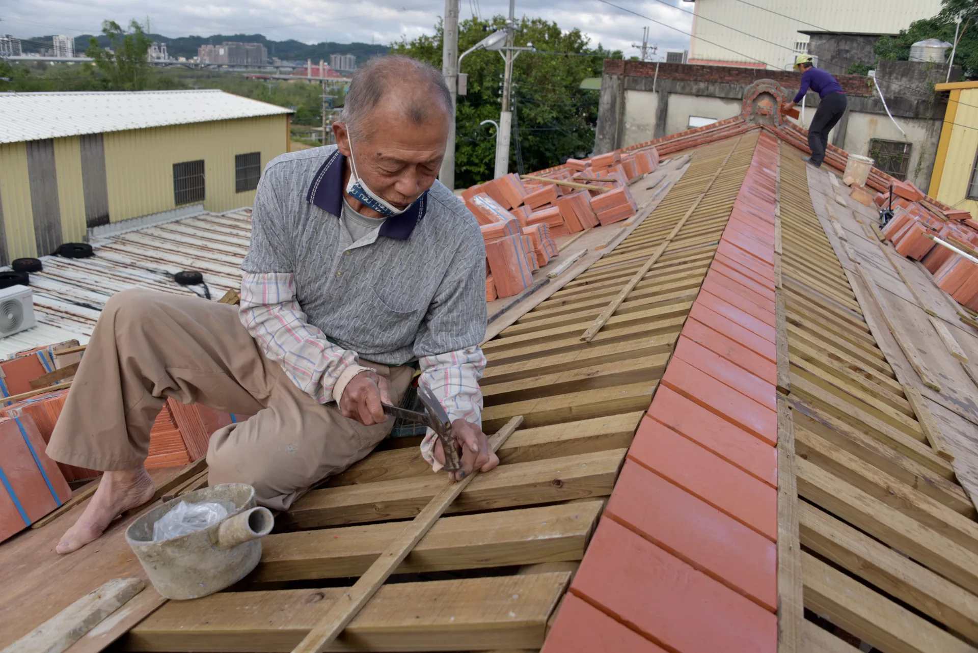 傅明光身手矯健，穿梭在屋頂施作屋瓦。圖為客傳會《傳、傳》劇照。古少騏攝