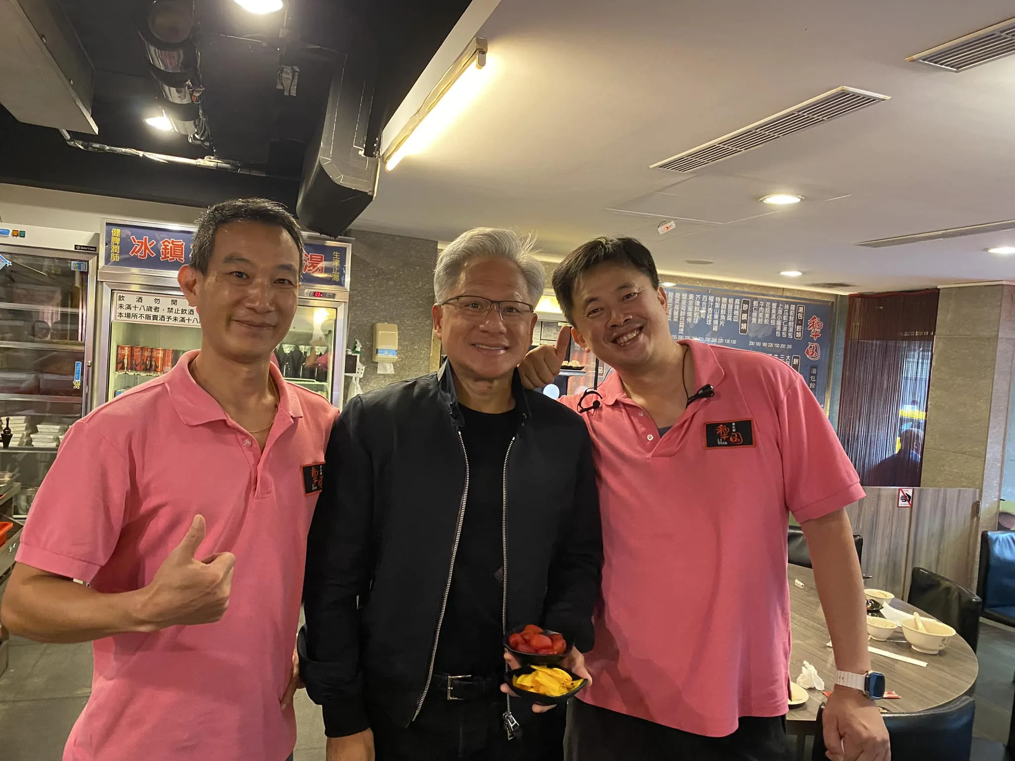 湯包館店員與黃仁勳合影留念，超親民的黃仁勳手中還拿著兩盤小菜。翻攝自蘇慶忠臉書