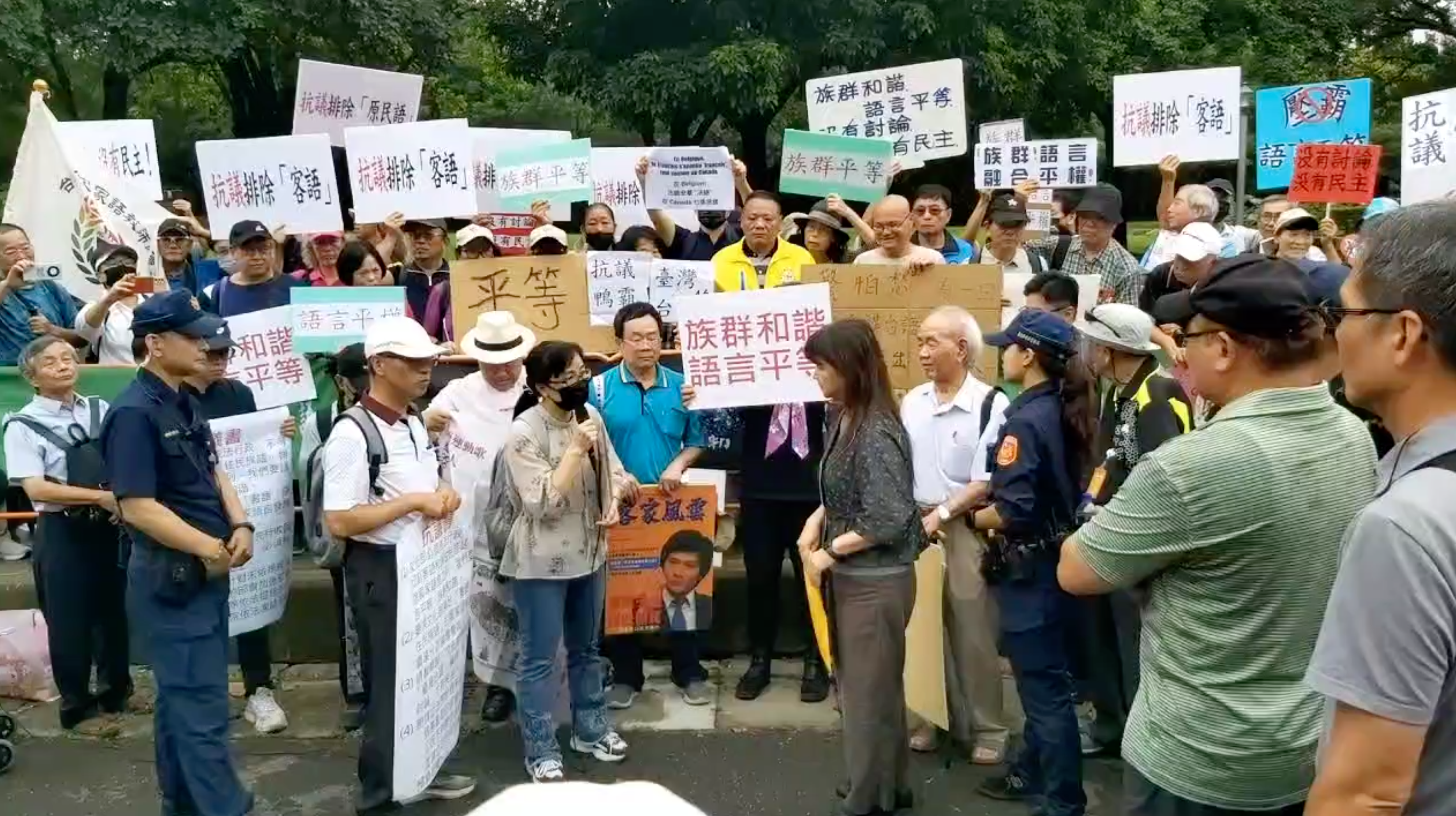 2024年,梁榮茂(右前女警旁,著白衣卡其褲者)與60多名客家鄉親到文化部舉辦的「臺灣台語北區論壇」抗議國家語言不能獨尊閩南語。謝國玄攝