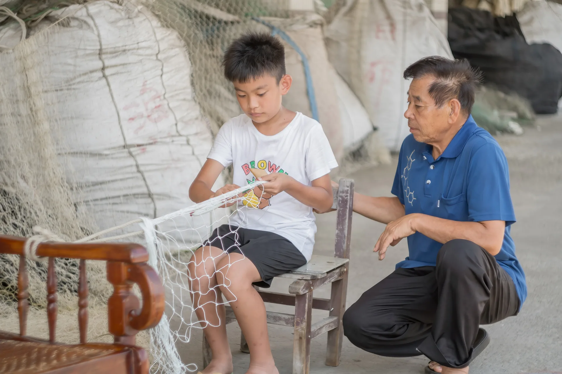 楊門圈盯著孫子一目又一目地編織著漁網，期許他能牢記「人不能忘本」。客傳會提供