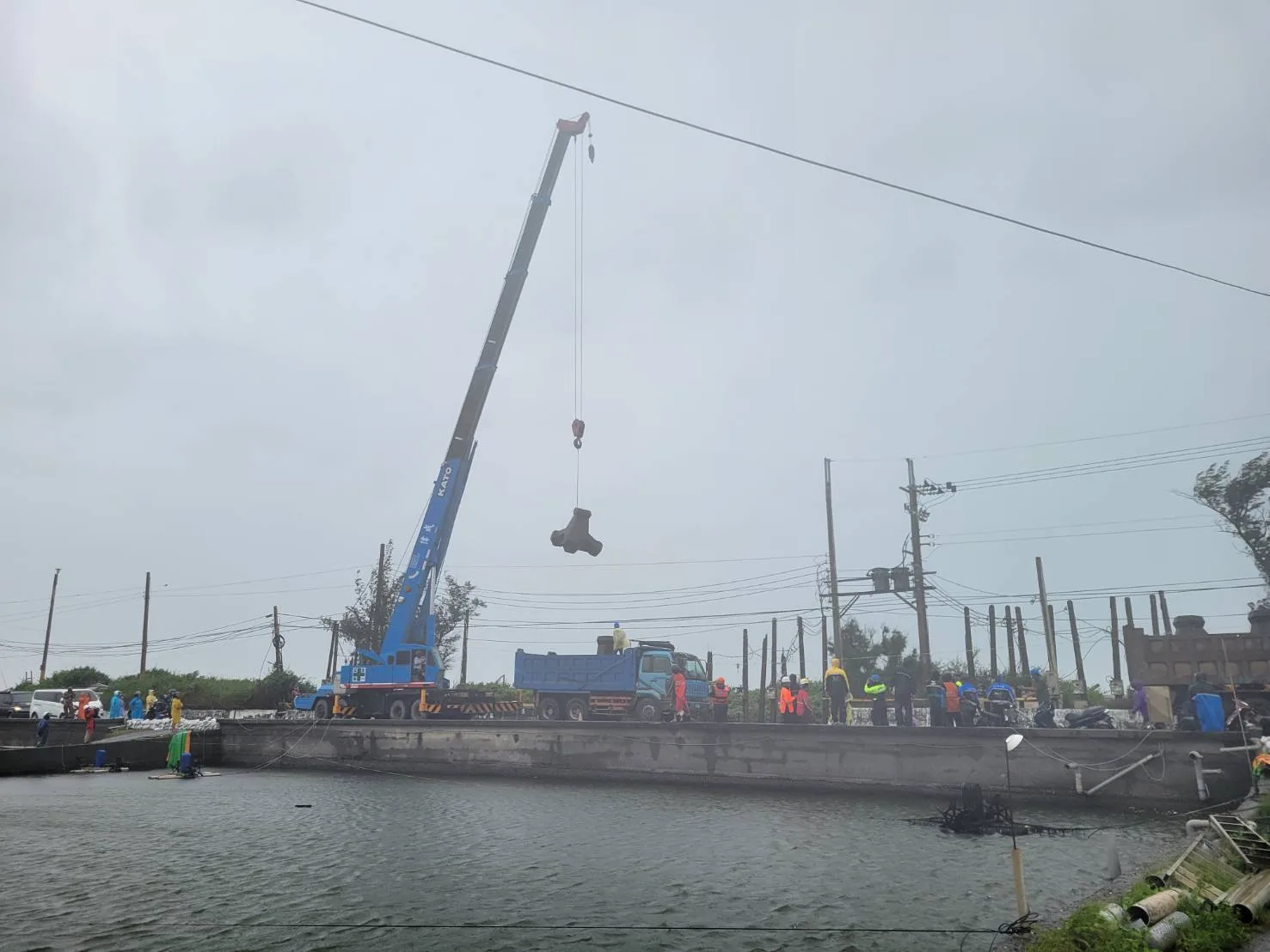 山陀兒颱風造成枋寮大庄海堤破堤,吊車吊起消波塊填補海提破口,全力搶修中。屏東縣政府提供