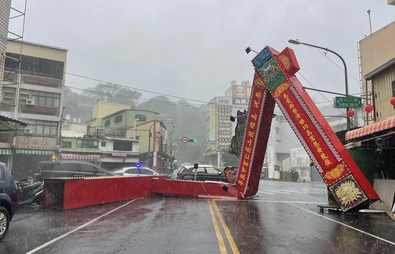 颱風山陀兒帶來強烈風雨，高雄市愛河旁河東路老樹遭強風連根拔起，橫倒路面阻礙交通。中央社