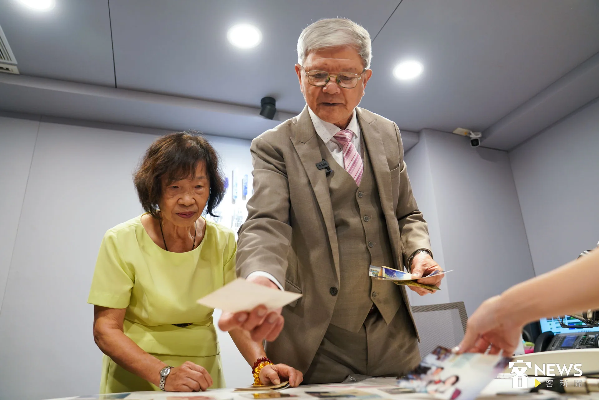 張民、古嫈夫妻拿著舊照片，講述當年做廣播的趣事。朱愷元攝