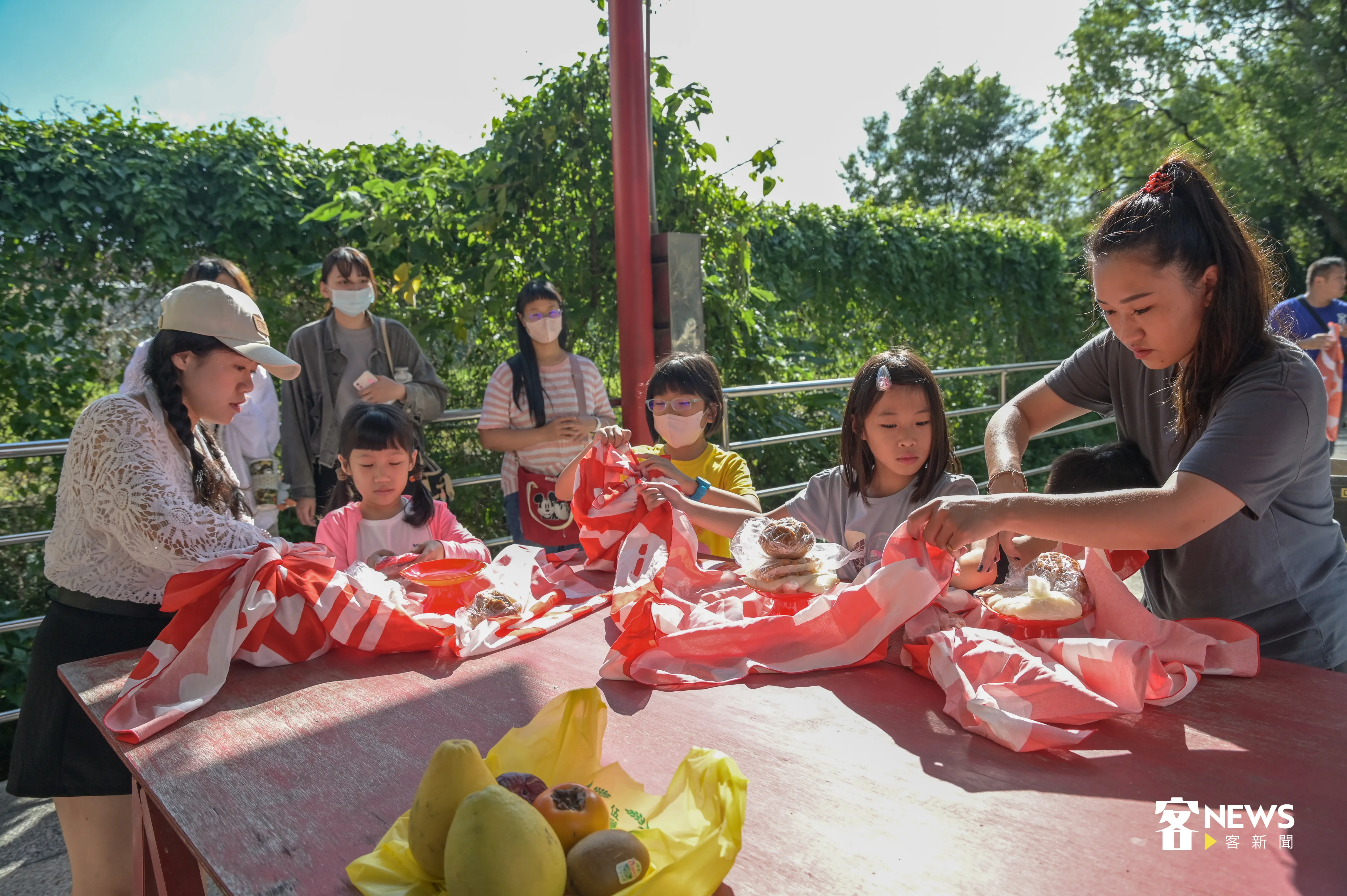 家長與孩子們,一起從包裹裡面拿出選定好的粄食敬拜伯公。洪俊傑攝