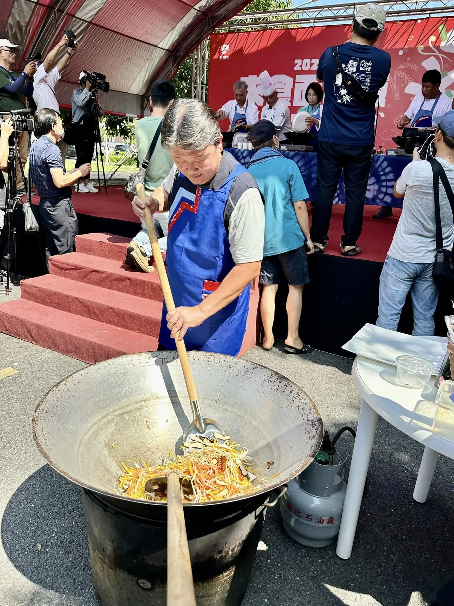 屏東縣長周春米在台上炒粄條，台下同時開鍋快炒。翻攝自竹田鄉公所 臉書