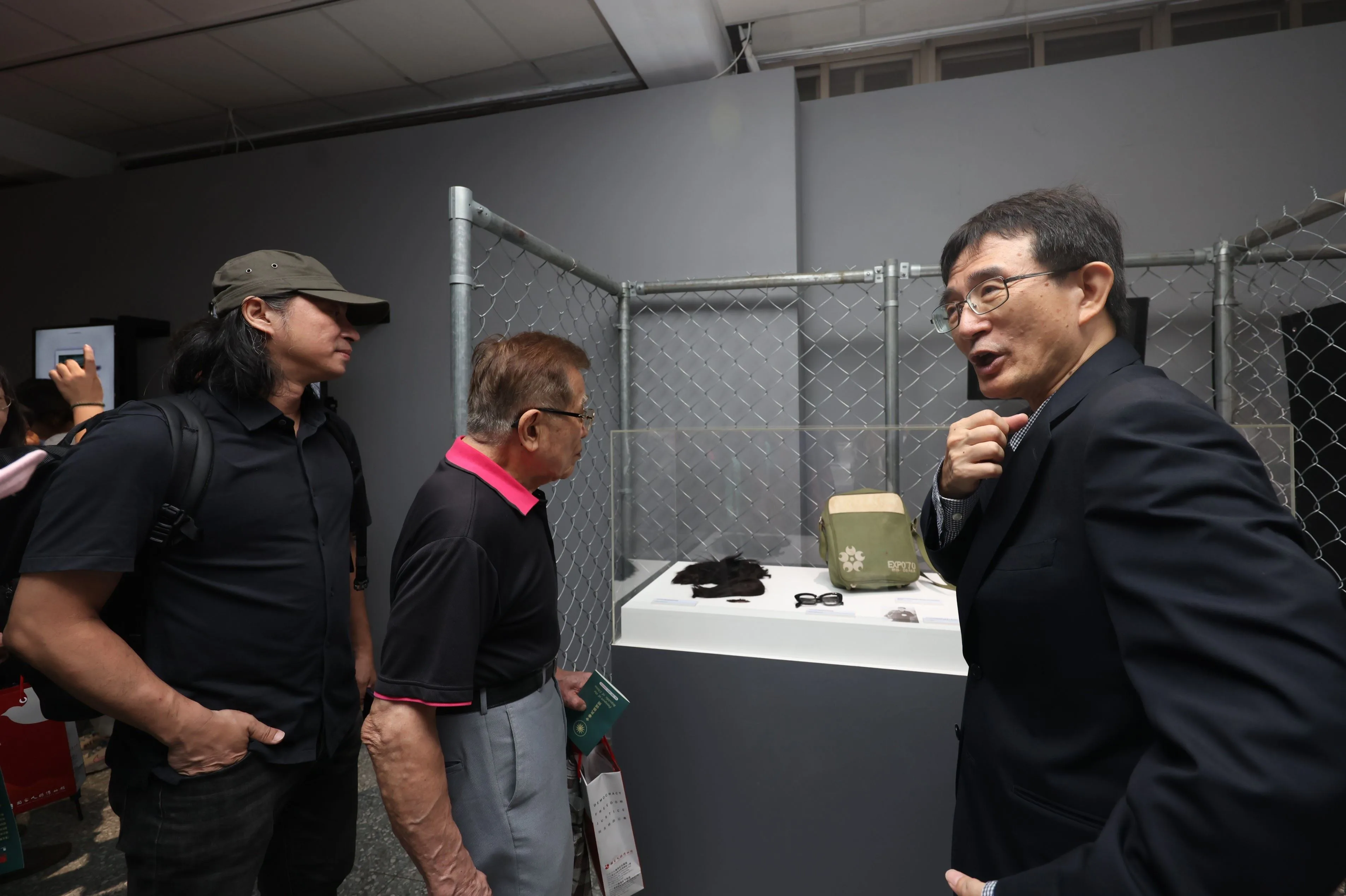 策展人薛化元為參展貴賓介紹彭明敏當年逃離臺灣，喬裝使用的假髮、眼鏡、背包、假義肢等。文化部提供
