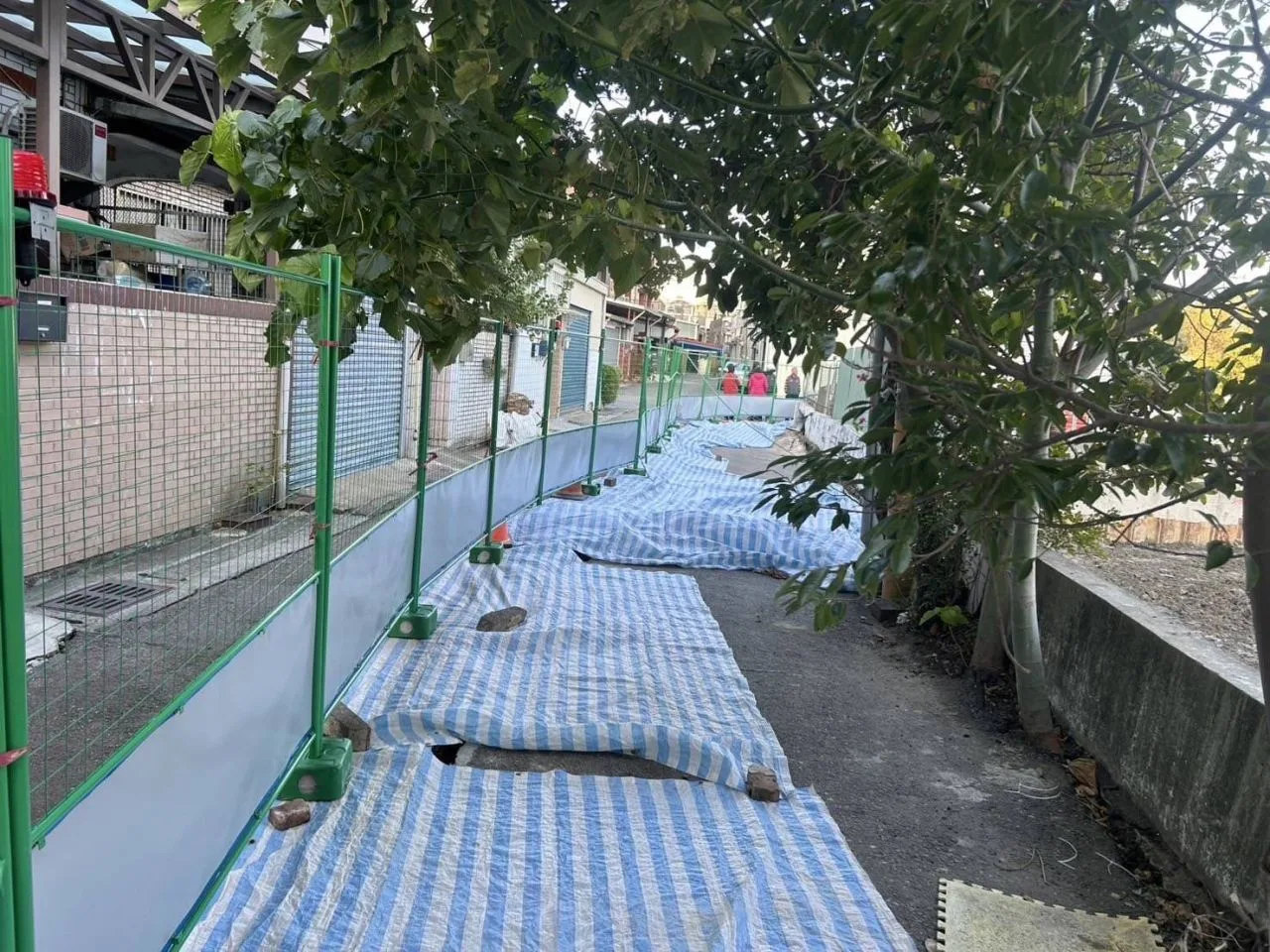 該建案工地所鄰部分路面已經進行封閉，並於沉陷處設置防水布、圍籬與警示標誌。苗縣府提供
