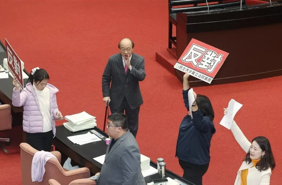 藍、白聯手表決通過共同提案,關於中央各機關及所屬歲出通案刪減用途別項目,以及如總刪減數未達新台幣939億7500萬元將另予補足。圖為民進黨團總召柯建銘(後中)帶領立委舉牌表達反對立場。中央社