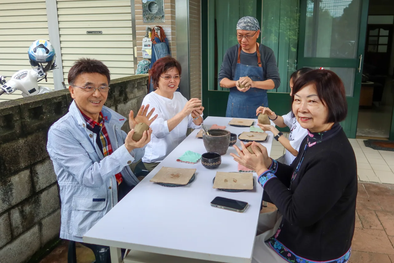 東億陶瓷廠負責人曾文賢（站者）指導王俊秀教授等人捏陶。何來美攝