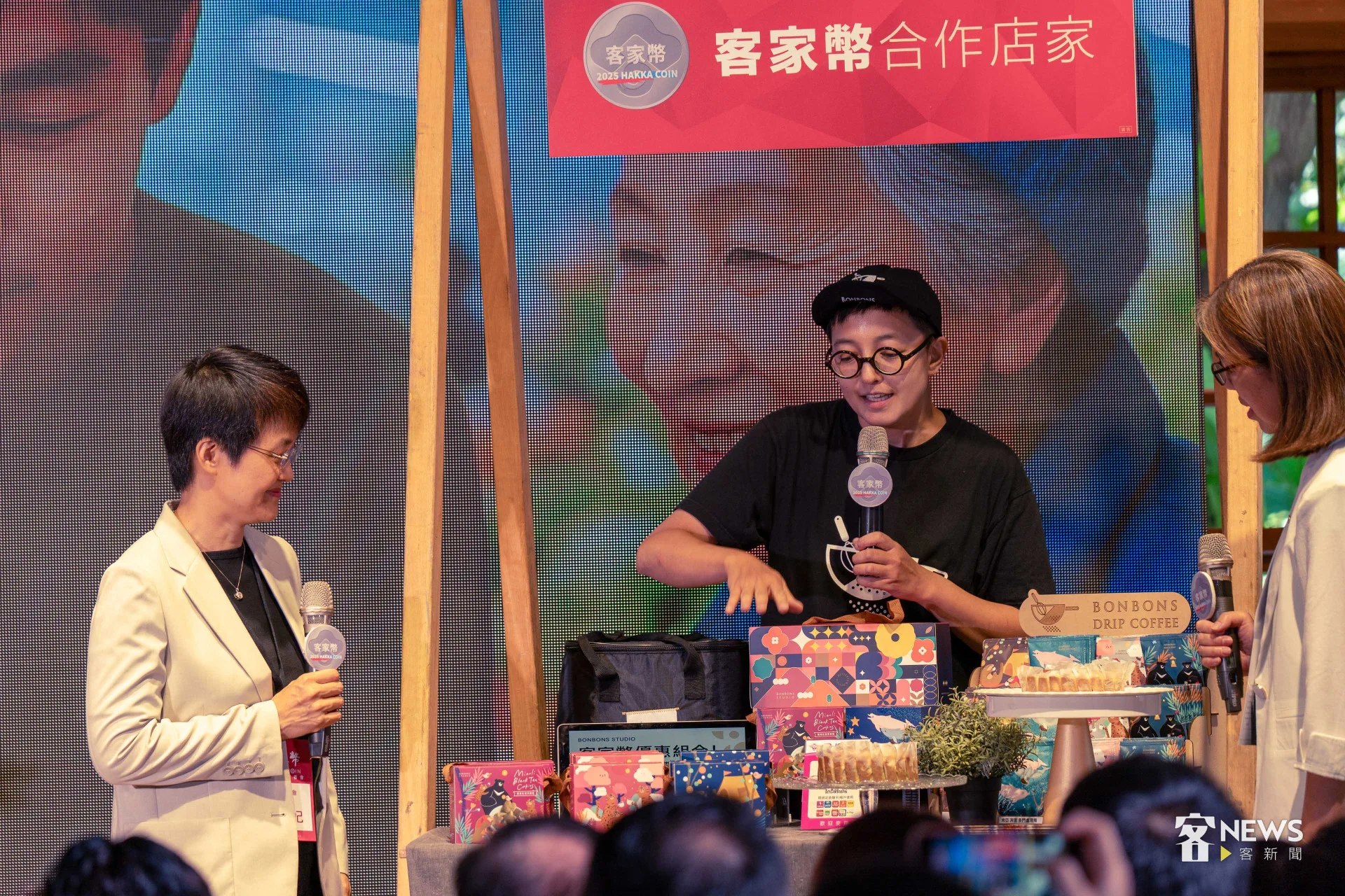 古秀妃（左）與示範店家展示客家幣使用流程。李台源攝