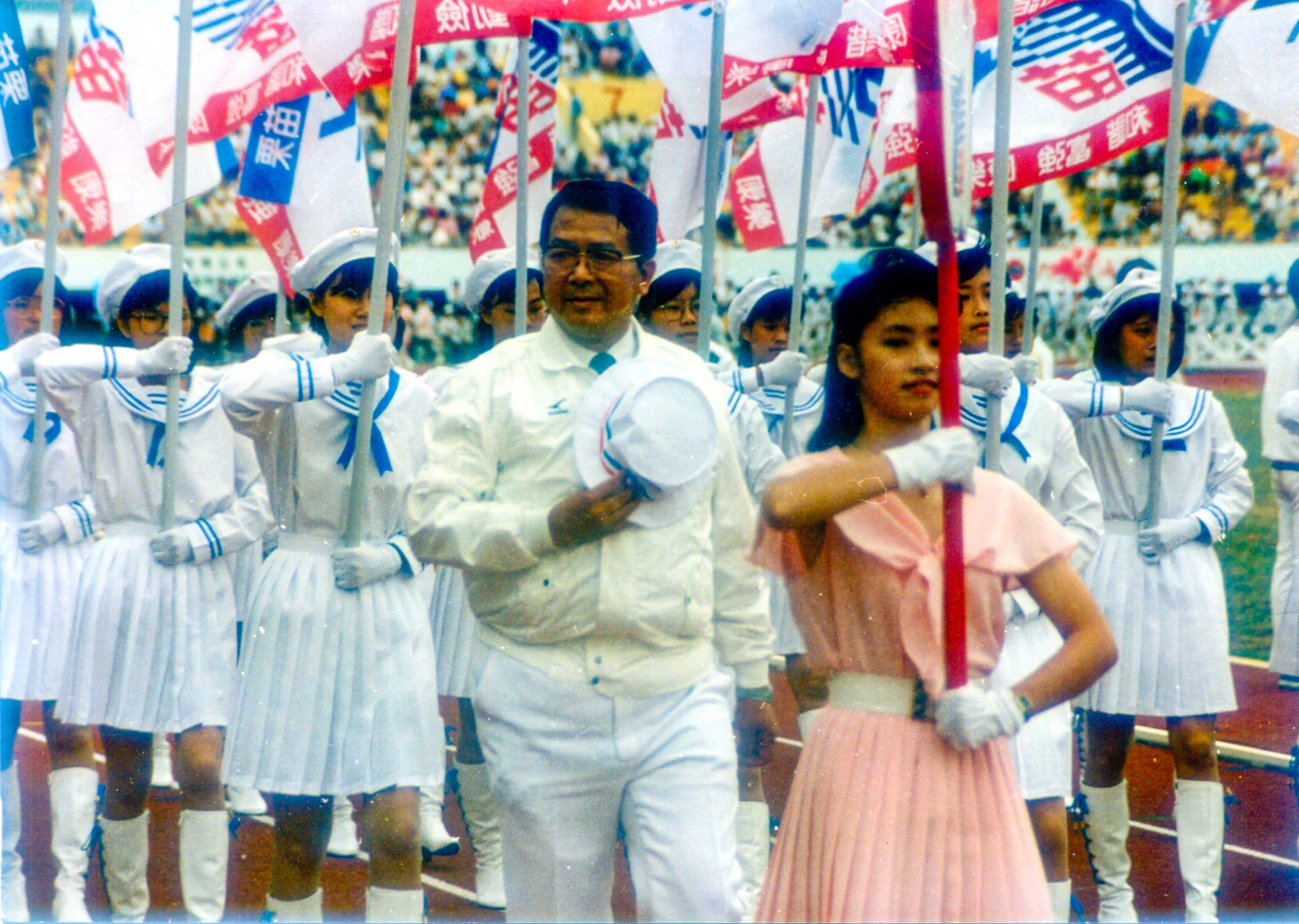 謝金汀（1936–2017）連任兩屆苗栗縣長，1988年苗栗縣主辦臺灣區運動會，他率運動員進場，神采奕奕。何來美攝