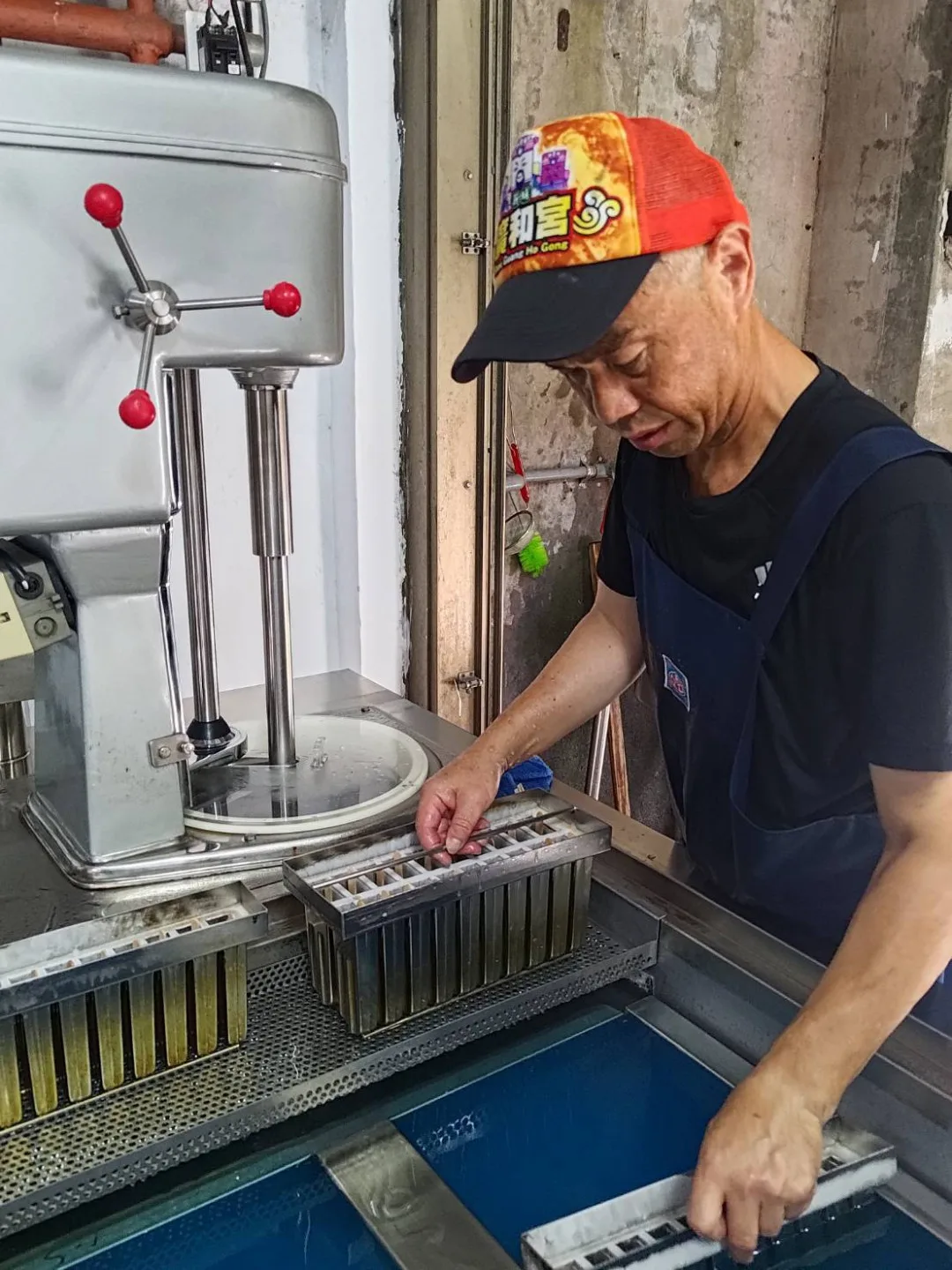 身穿殺魚圍裙的陳智弘將模具浸入冷劑中，一旁是製作綿綿冰的攪拌機。陳智弘提供