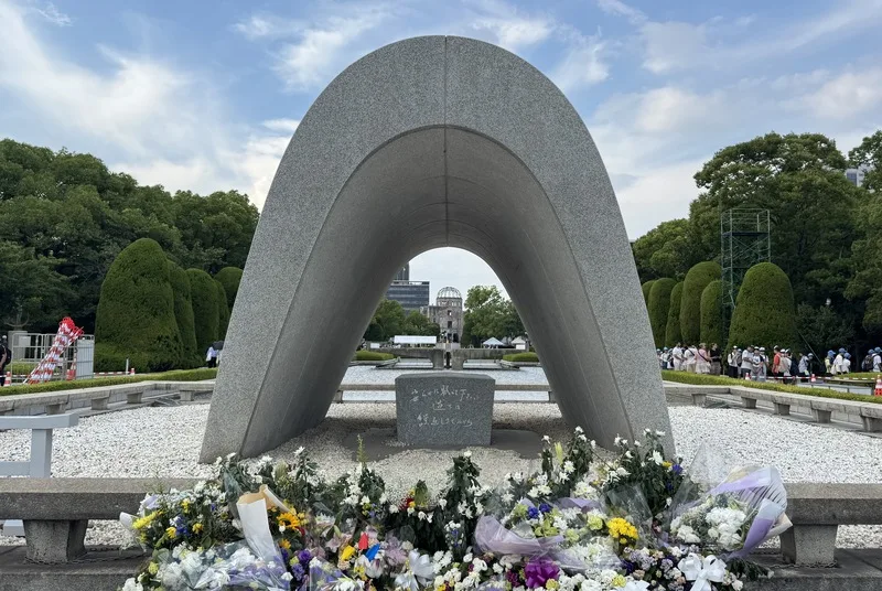 廣島市和平紀念公園內的原爆死歿者慰靈碑刻有「請安息吧，戰爭錯誤不再重演」碑文，可見到訪客致意、獻花。中央社