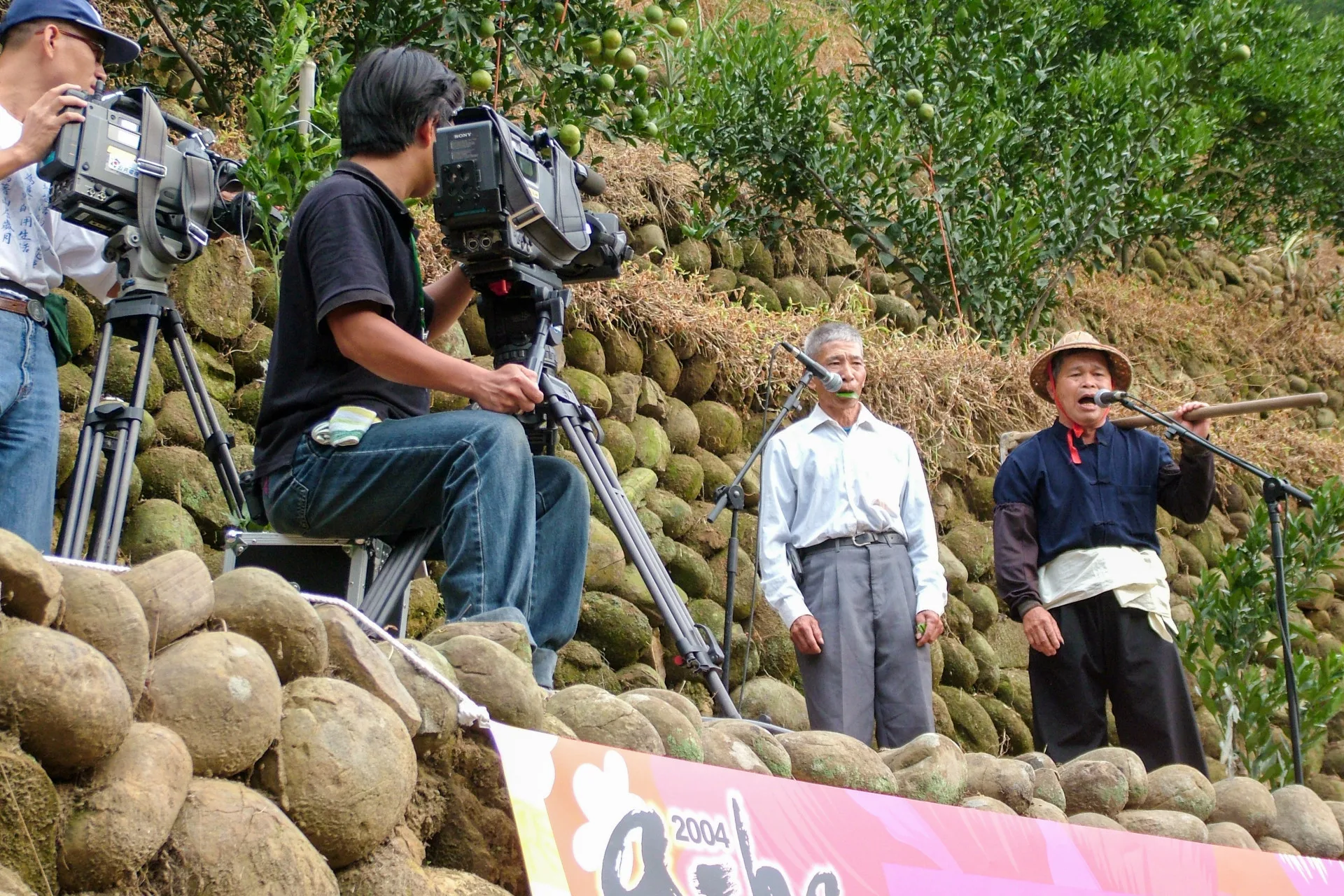 山歌大師林德富,他在模仿原生態山歌,這是他(右一)在鹿寮坑地景音樂會演唱神情,當時客委會主委羅文嘉還到場給他鼓勵,這是表演式山歌,也是一種衍生態山歌。楊國鑫攝
