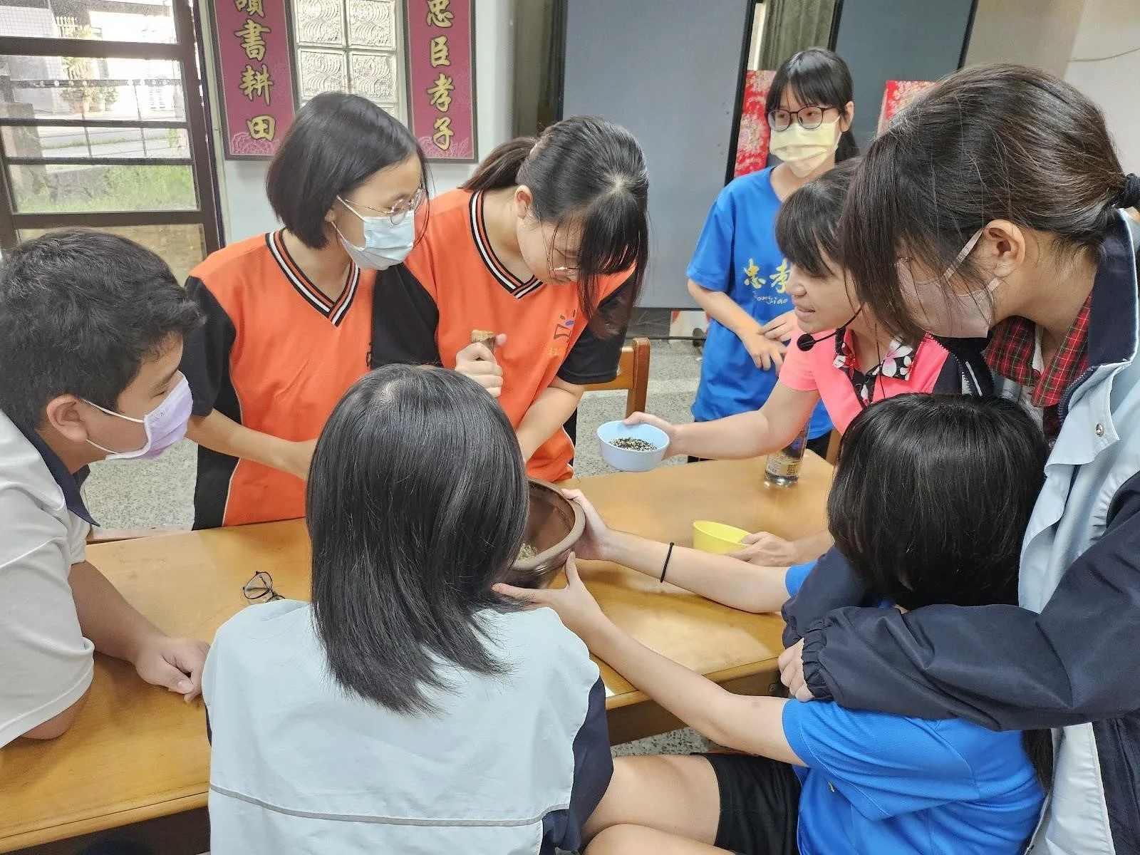 台南忠孝國中學生製作擂茶,合力把材料磨成粉末,還能夠邊「打嘴鼓」。客委會提供