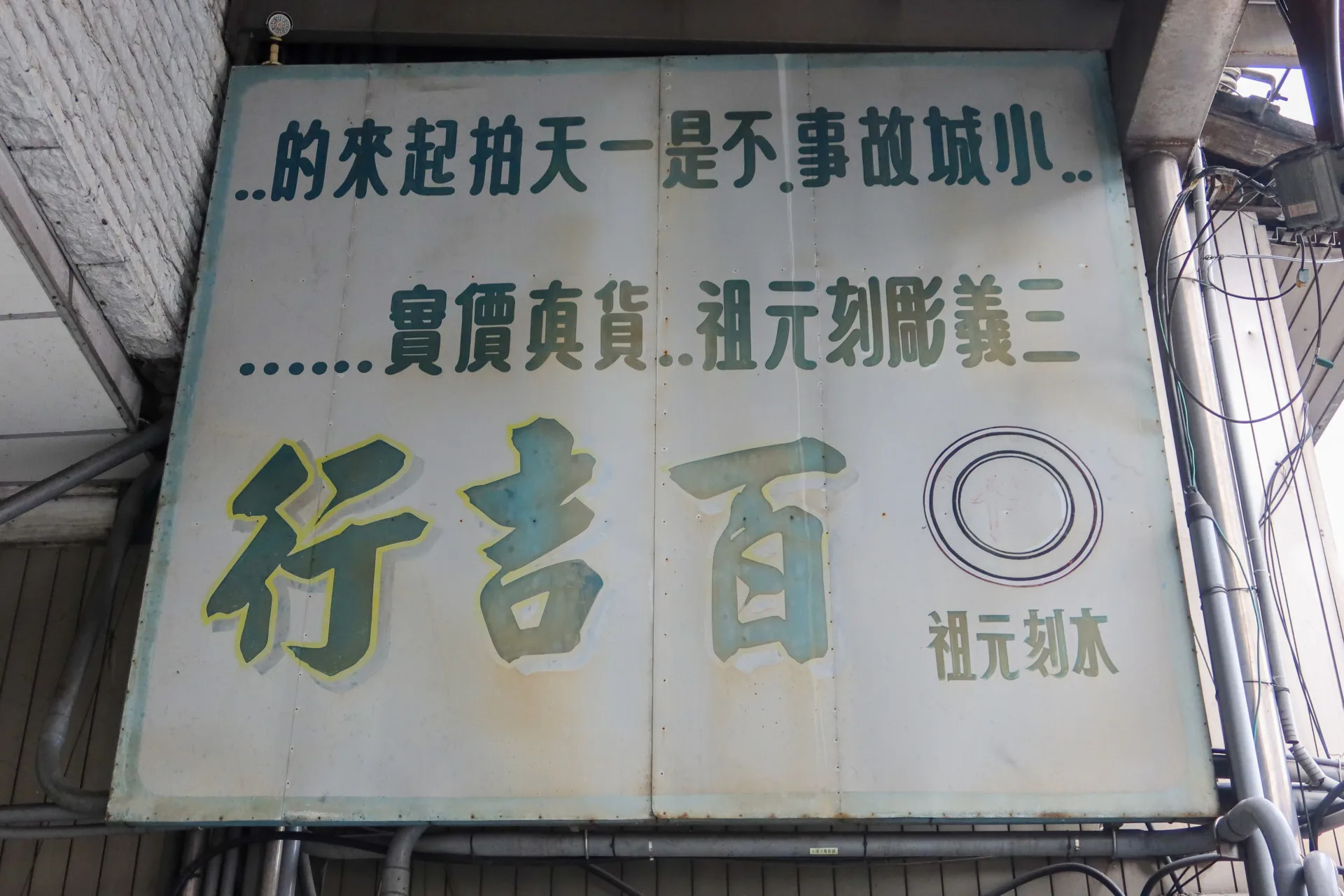 三義百吉行樓下留下「小城故事不是一天拍起來的……三義雕刻元祖……貨真價實……木刻元祖百吉行」的牌子。何來美攝