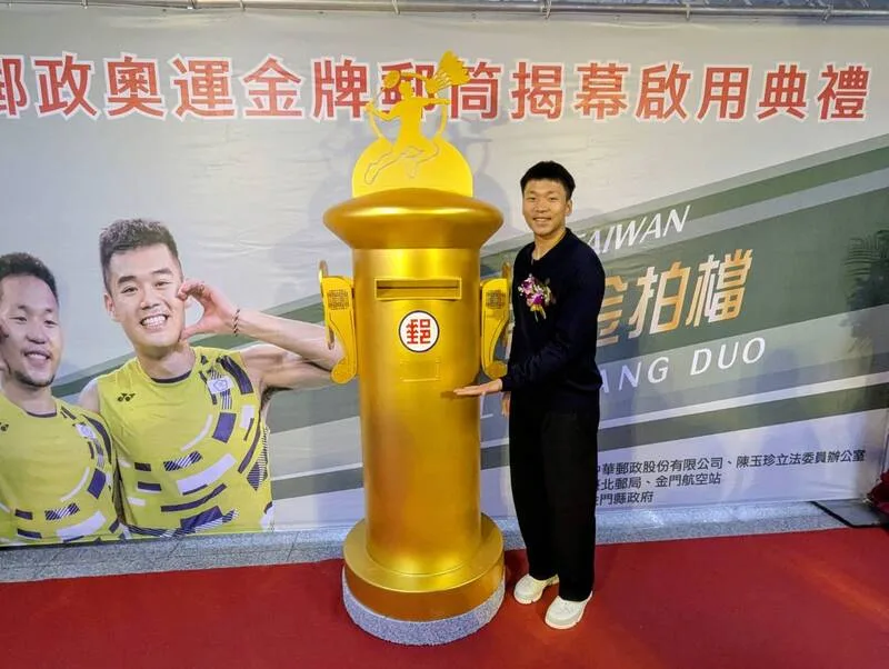 李洋9日接任運動部長，也是首名有金色郵筒的部長。中華郵政在李洋家鄉金門的航空站中設置奧運金色郵筒，圖為1月16日啟用典禮李洋與金色郵筒合影。中央社