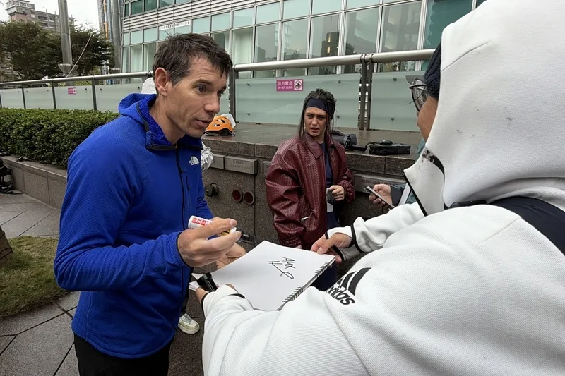 美國自由攀岩好手霍諾德（Alex Honnold）（左）將於台灣時間24日挑戰徒手攀登台北101，他21日上午試爬，幫熱情粉絲簽名。中央社
