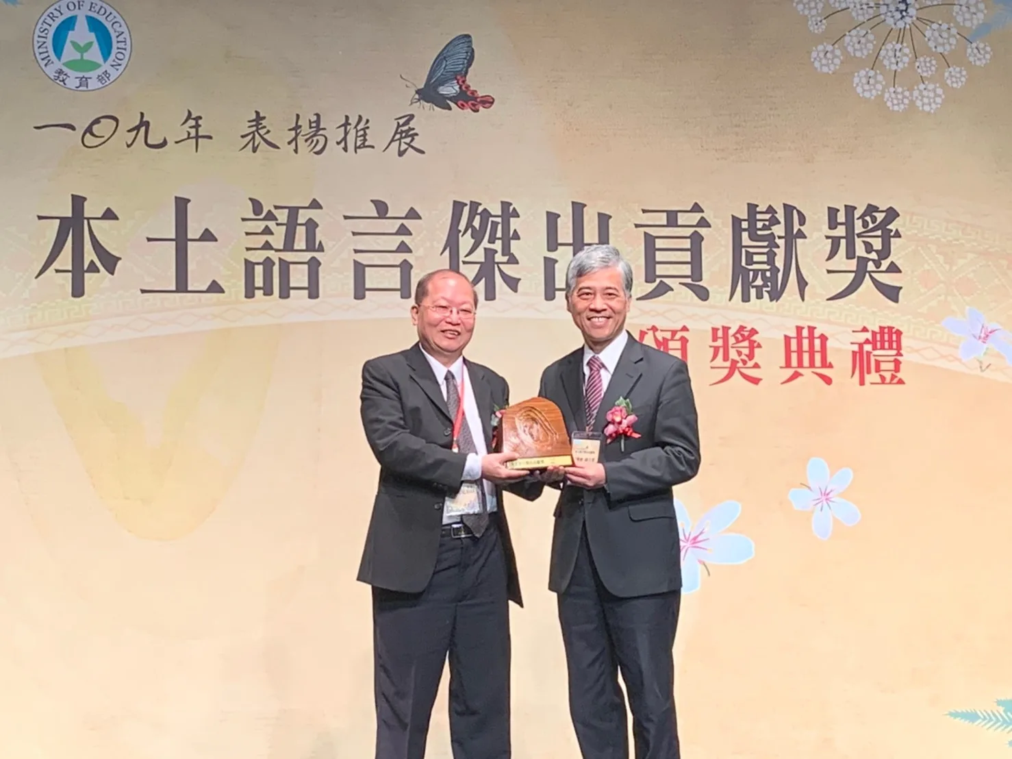 張義品(左)於2020年榮獲教育部本土語言傑出貢獻獎,他從客委會前副主委范佐銘手中接下獎座。《客家》雜誌提供