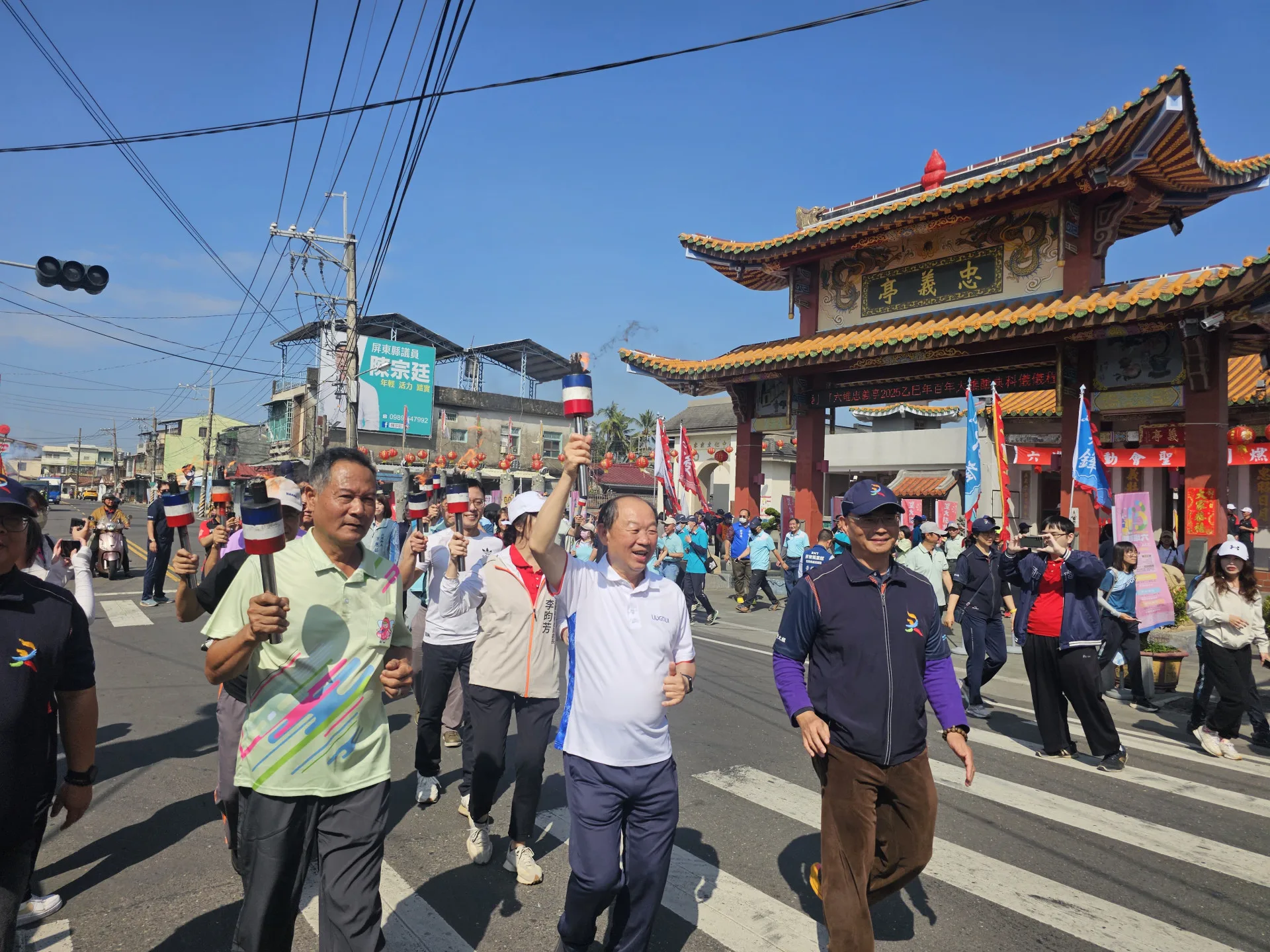 聖火引燃典禮為第61屆六堆運動會揭開序幕，由佳冬鄉長賴文一及客發中心主任謝勝信（中）帶領六堆各鄉區代表自忠義亭起跑，為期3天的聖火遶境。客委會提供