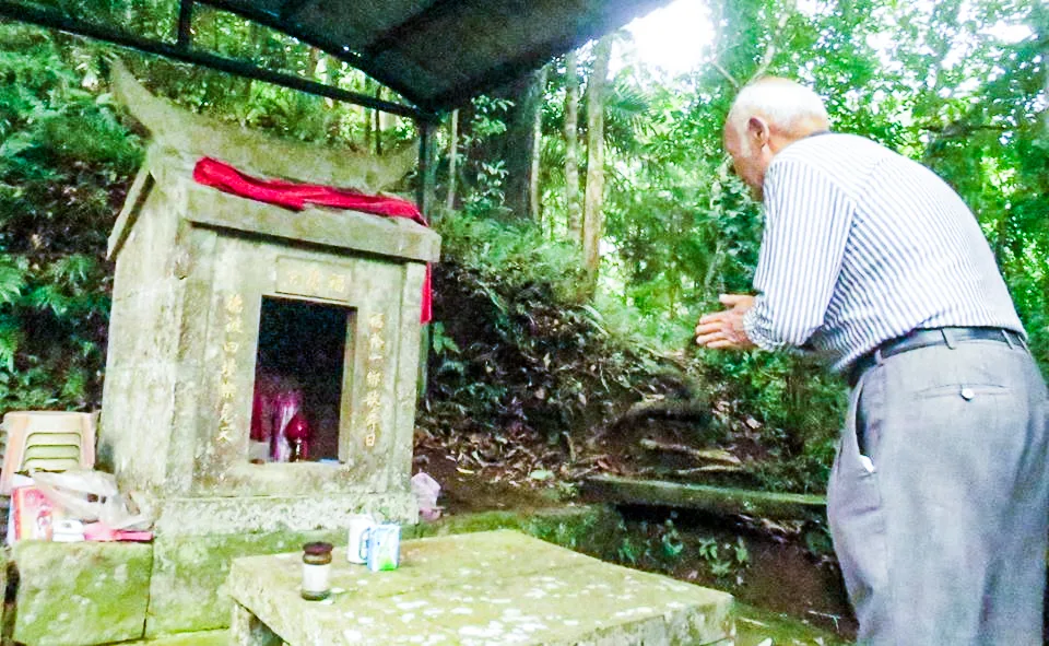 北埔老農在山邊伯公祠前虔誠合掌。對許多客家人而言，人生大小事不必遠求大廟，伯公便是最親近的守護神。陳權欣攝